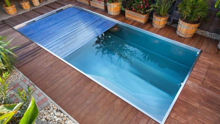 Rectangular pool with slatted cover on wooden deck