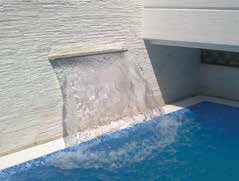 Waterfall spout pours clear water into rectangular outdoor pool, cascading down a curved stone ledge against a textured light wall, creating ripples and splashes on the blue surface.