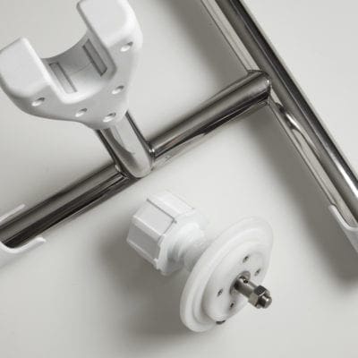 A sliding shower door roller and U shaped bracket lie disassembled on a white surface, showing a white plastic wheel with metal pin alongside polished chrome tubular rails.
