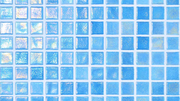A grid of small square iridescent blue mosaic tiles reflects light, arranged in white-grouted rows and columns forming a glossy wall or pool surface.
