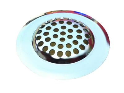 Polished circular metal sink strainer with concentric holes covering a drain, resting on a white background, reflective chrome rim showing faint colored reflections.