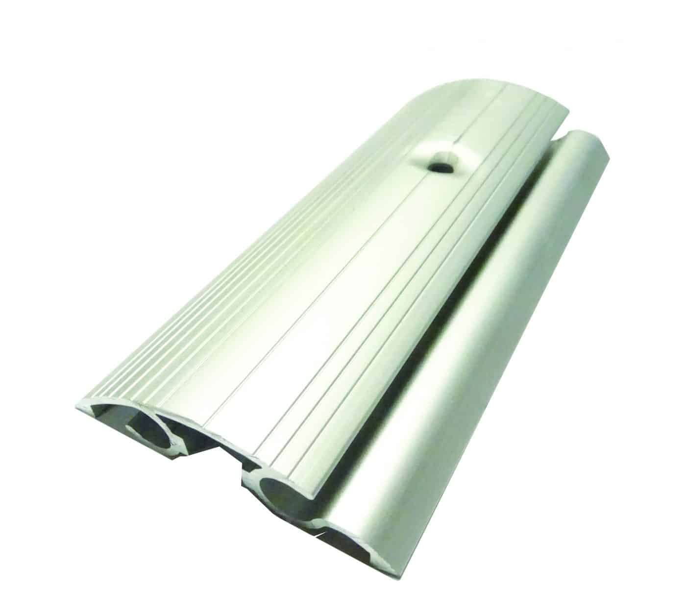 Aluminum threshold strip rests angled, revealing twin hollow channels, ridged surface and central screw hole, photographed against a plain white background.