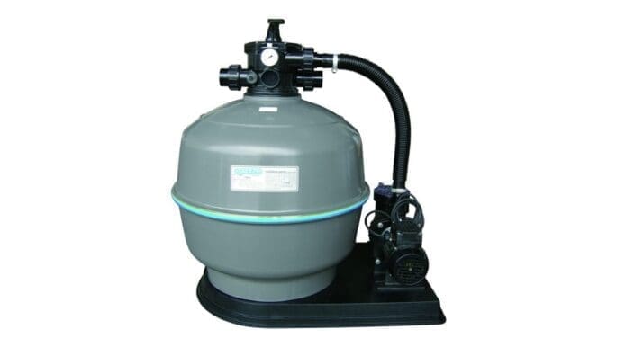Large gray cylindrical pool sand filter sits on a black base, connected by a corrugated hose to a black pump unit beside it against a white background. Label reads WATERCO (remaining small text illegible).