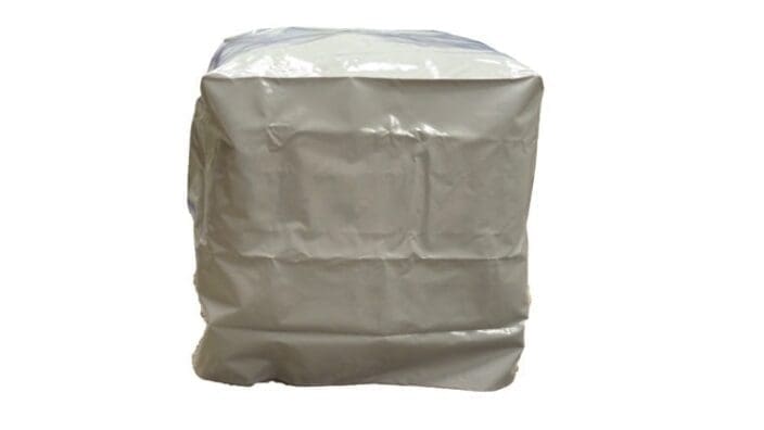 A crinkled white plastic-wrapped rectangular bundle sits stationary, tightly wrapped and slightly misshapen, isolated against a plain white background suggesting studio or product photography.