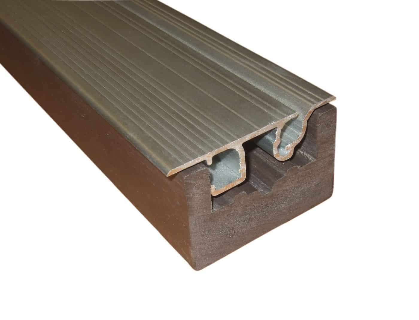 Composite wood block supporting an aluminum stair-nosing profile; the metal strip rests fitted into a grooved channel, showing a ridged top and hollow underside, photographed against a white background.
