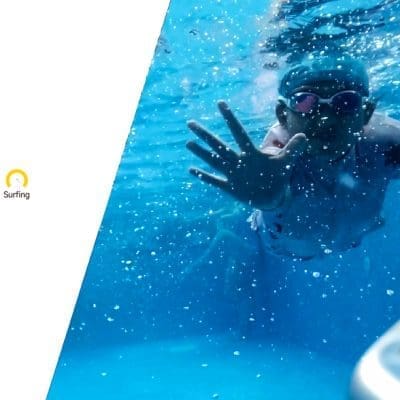 Child wearing goggles reaches a hand toward the camera while swimming underwater in a pool, white panel at left reads: 5 swimming training modes Beginner Intermediate Advanced Endurance Surfing 3-Types of control Touch Pad controller /Remote control/APP control